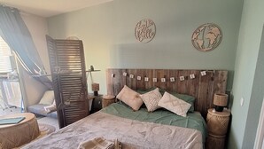 A bedroom with a bed, pillows, a wooden headboard, a globe decoration, and a small round table. - A tropical break, facing the Caribbean Sea in an exceptional setting (Le Diamant)
