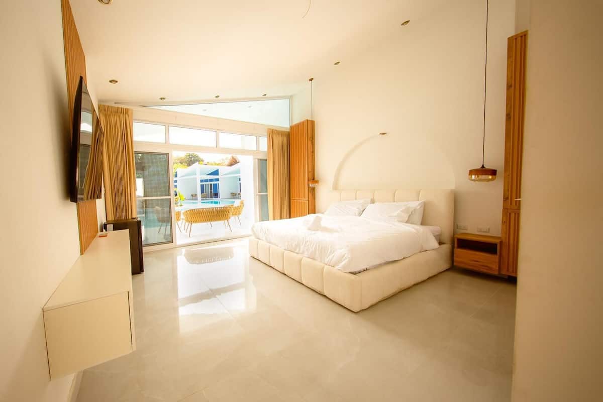 Une chambre moderne dotée d’un grand lit, d’une télévision et donnant sur une piscine extérieure.