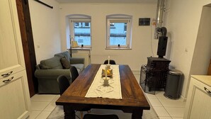 A dining area with a wooden table, two chairs, a small rug, and a ceiling light fixture.