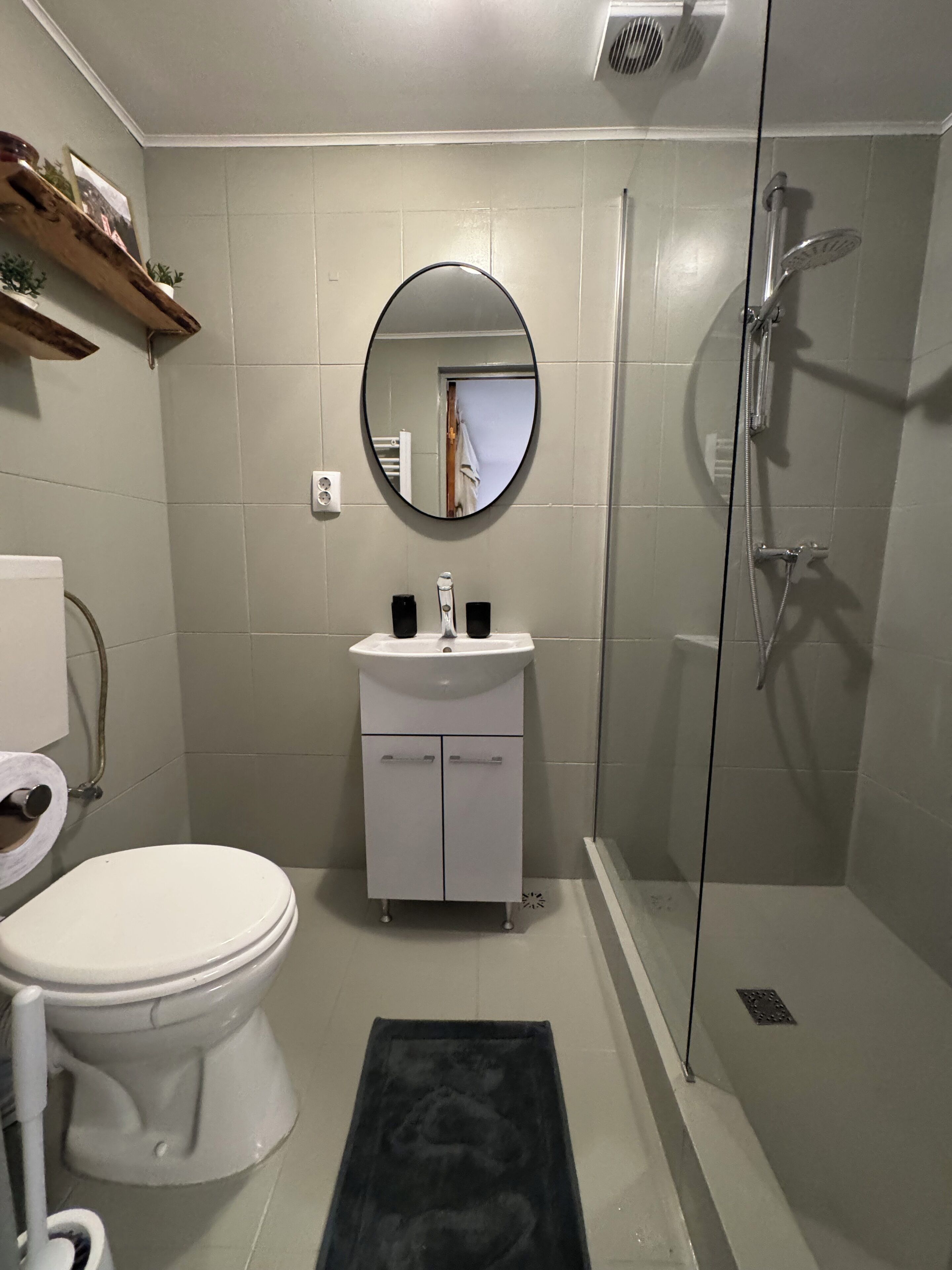Un bagno con il water, lavandino, specchio e doccia.