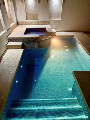 A rectangular indoor swimming pool with clear blue tiles, surrounded by stone steps and walls. - Villa Alberca, Bar y Terraza Privada (La Paz)