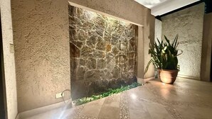 A stone wall with a textured surface, a potted plant, and a tiled floor with a geometric pattern. - Villa Alberca, Bar y Terraza Privada (La Paz)