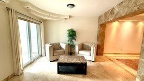 A spacious living room with a large window, two sofas, a coffee table, and a potted plant. - Villa Alberca, Bar y Terraza Privada (La Paz)