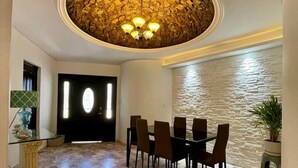 A dining area with a stone wall, a chandelier, and a table set for six. - Water & Flower House (La Paz)