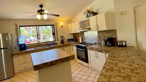 A kitchen with a central island, a stove, microwave, and cabinets. - Water & Flower House (La Paz)