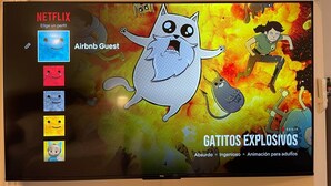Uma TV exibindo a interface da Netflix com o título 'GATITOS EXPLOSIVOS' e opções para 'Elige un perfil' e 'Airbnb Guest'.