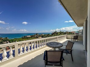 Ein Balkon mit Blick auf das Meer, ein runder Tisch und zwei Stühle.