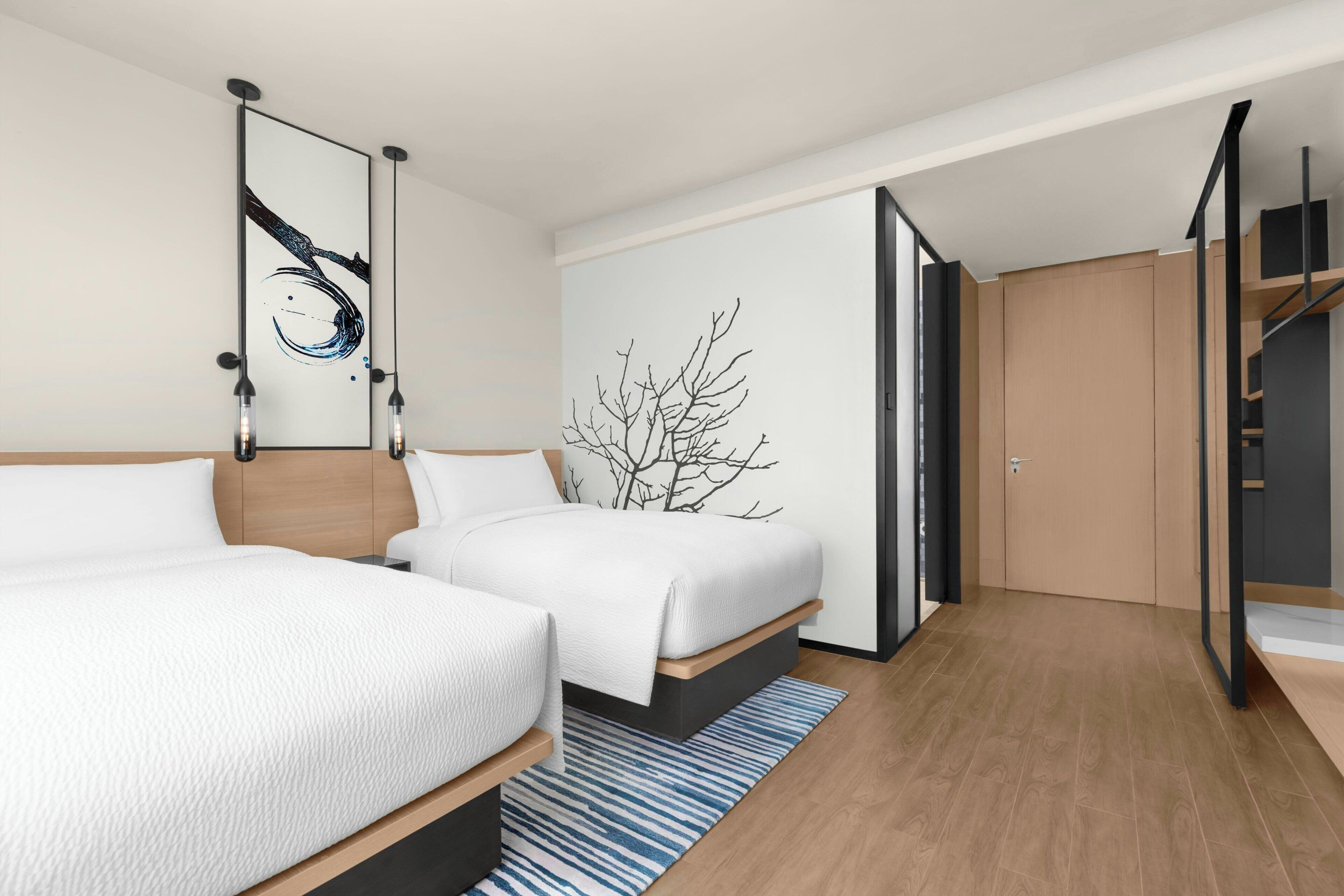 Una habitación de hotel moderna con dos camas, un ventanal amplio y un diseño minimalista.