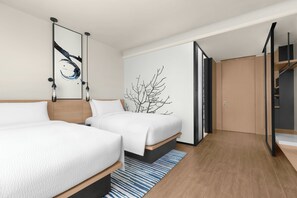 Une chambre d’hôtel moderne avec deux lits, une grande fenêtre et un design minimaliste.