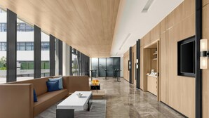 A modern interior with a long corridor, a seating area with a sofa and coffee table, and a kitchen area with cabinets and a TV. - Fairfield By Marriott Cebu Mactan (Lapu-Lapu)
