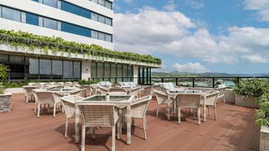 A rooftop terrace with wicker furniture and a view of the sea. - Fairfield By Marriott Cebu Mactan (Lapu-Lapu)