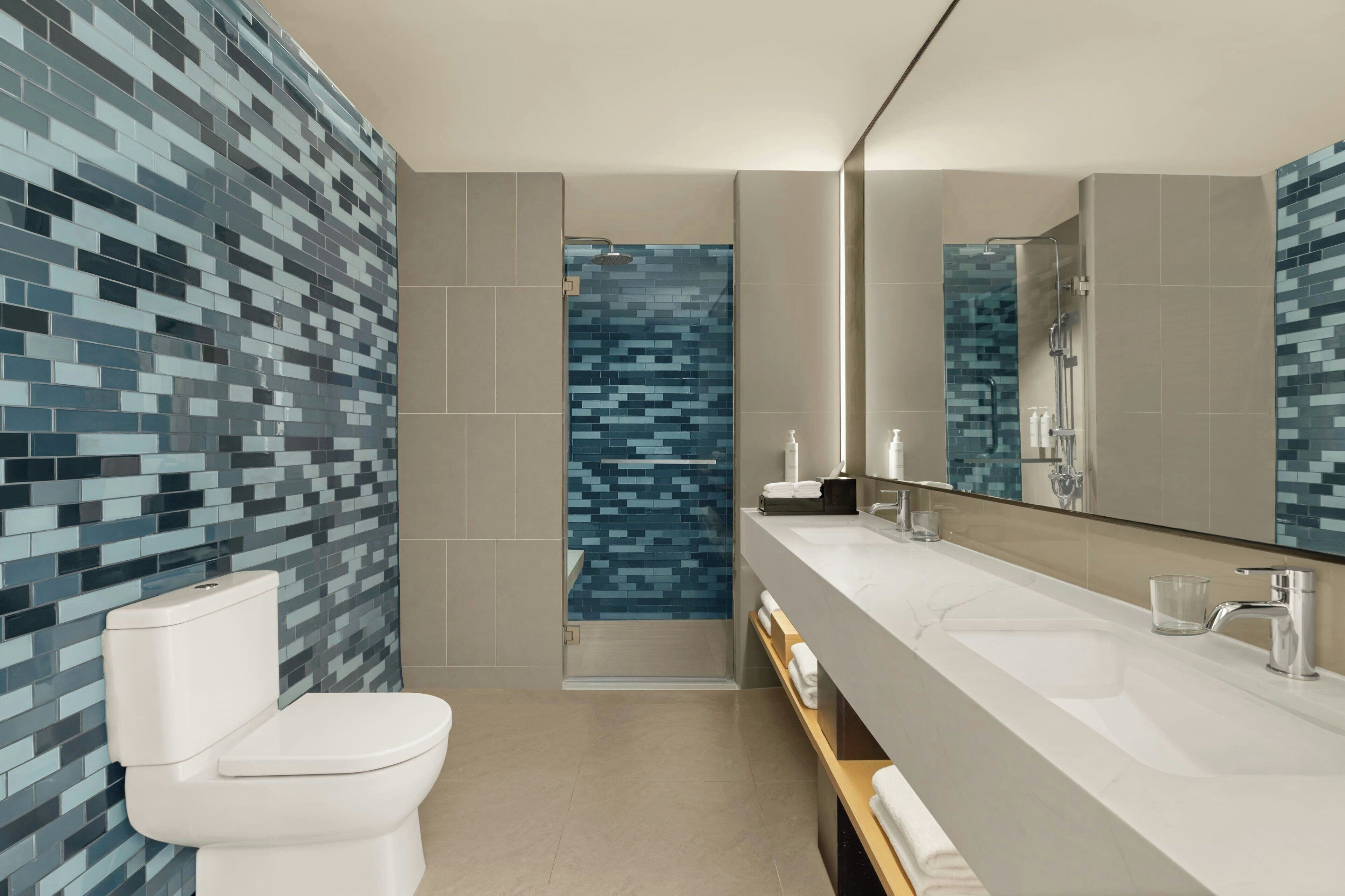 Un baño moderno con inodoro, ducha y tocador con espejo.