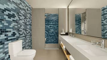 Un baño moderno con inodoro, ducha y tocador con espejo.