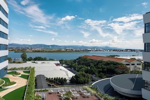 Un hotel con terraza en la azotea, vista a un lago y montañas al fondo.