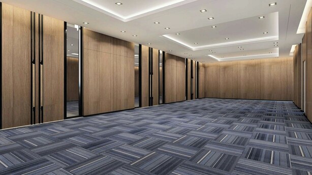 Une salle de conférence dotée d’un tapis à motifs chevrons, de murs lambrissés et d’un éclairage encastré au plafond.