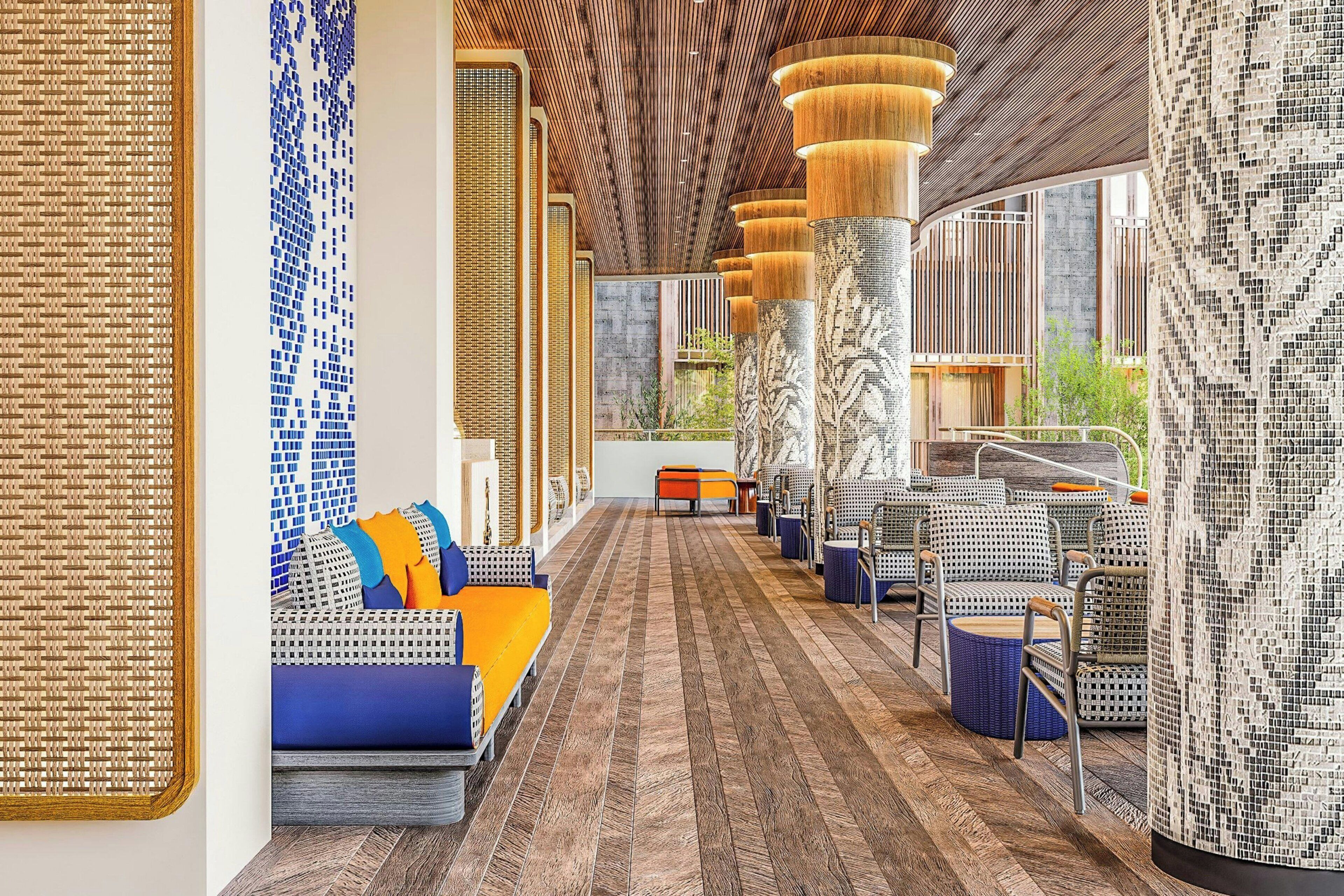 A modern interior with a patterned floor, seating areas, and a view of greenery outside.