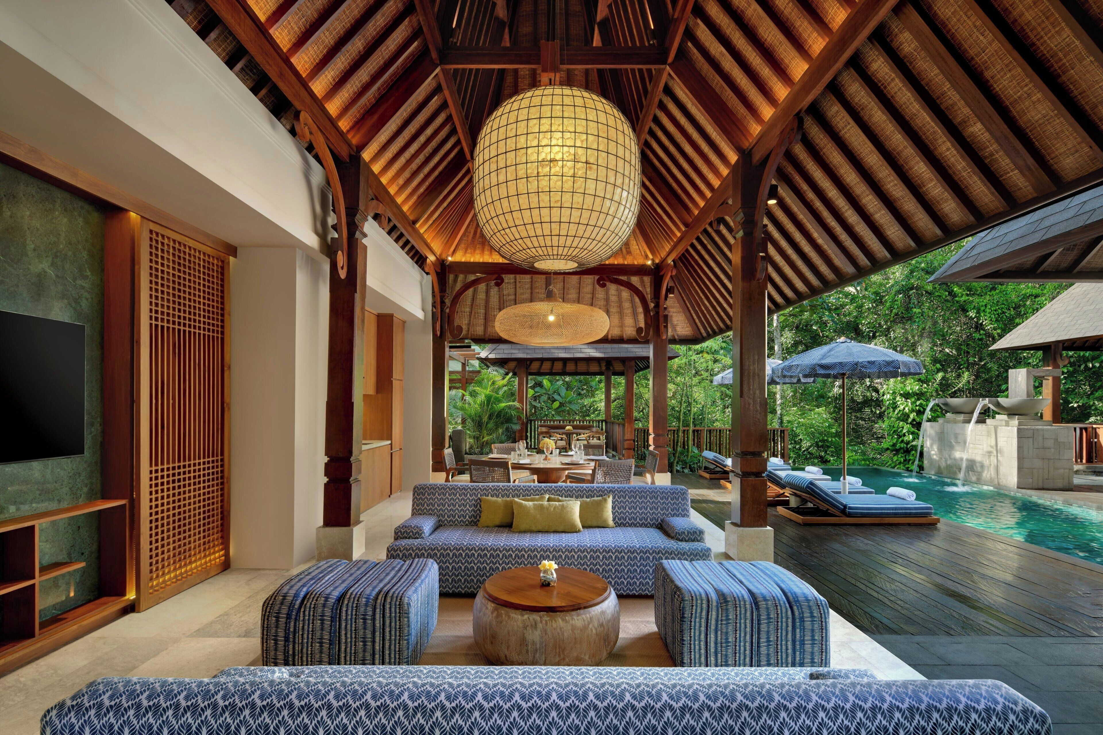 Amplo espaço interno com piscina, área de estar externa e uma luminária pendente grande.