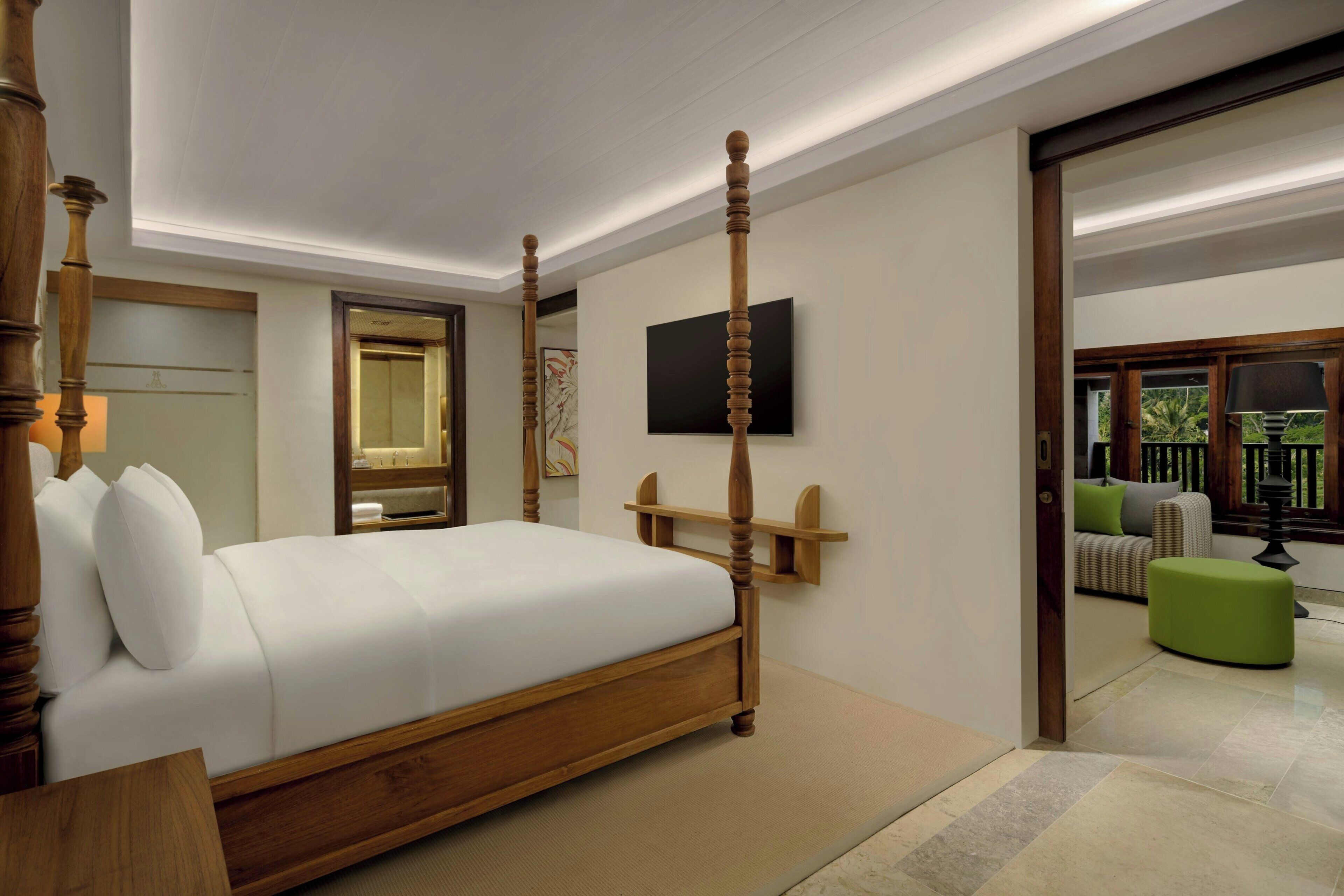 Een hotelkamer met een hemelbed, een aan de muur bevestigde televisie en uitzicht op het landschap door een raam.