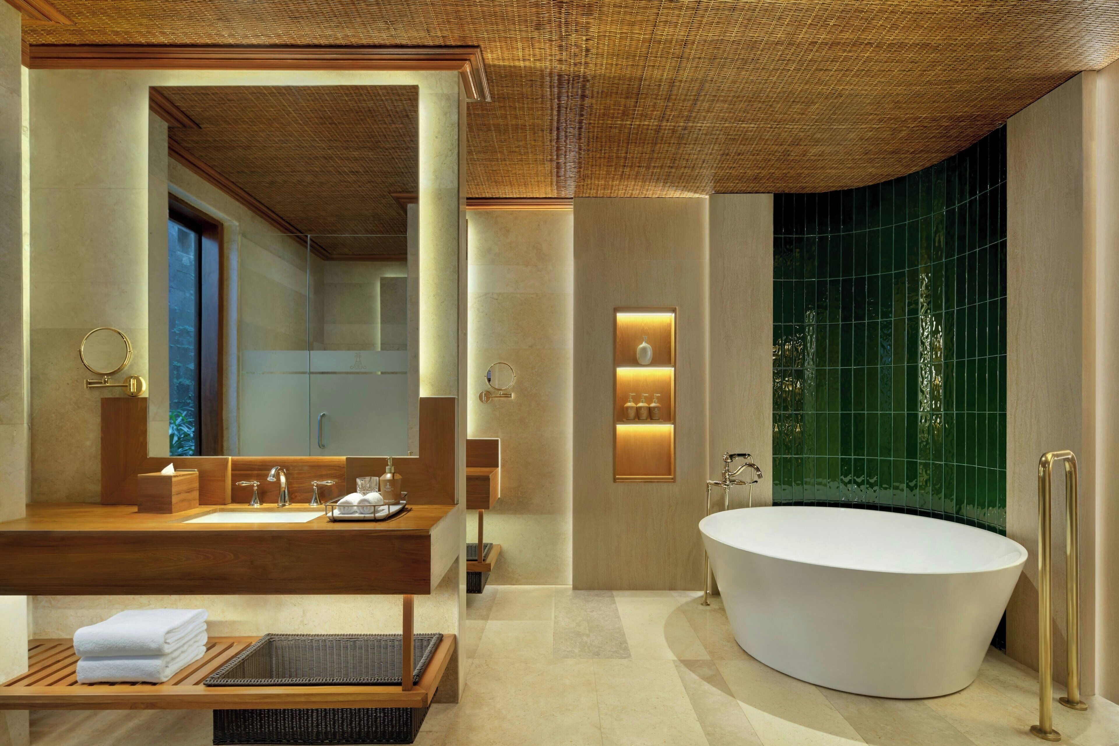 Un baño moderno con una bañera independiente, un espejo grande y un mueble de tocador con encimera de madera.