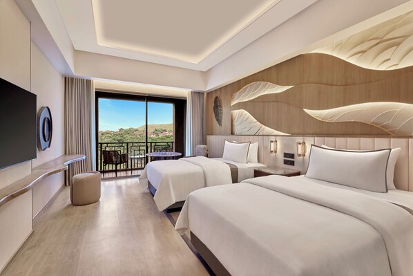A hotel room with two beds, a TV, a balcony with a table and chairs, and a view of the landscape. - The Westin Jaipur Kant Kalwar Resort And Spa (Amer)