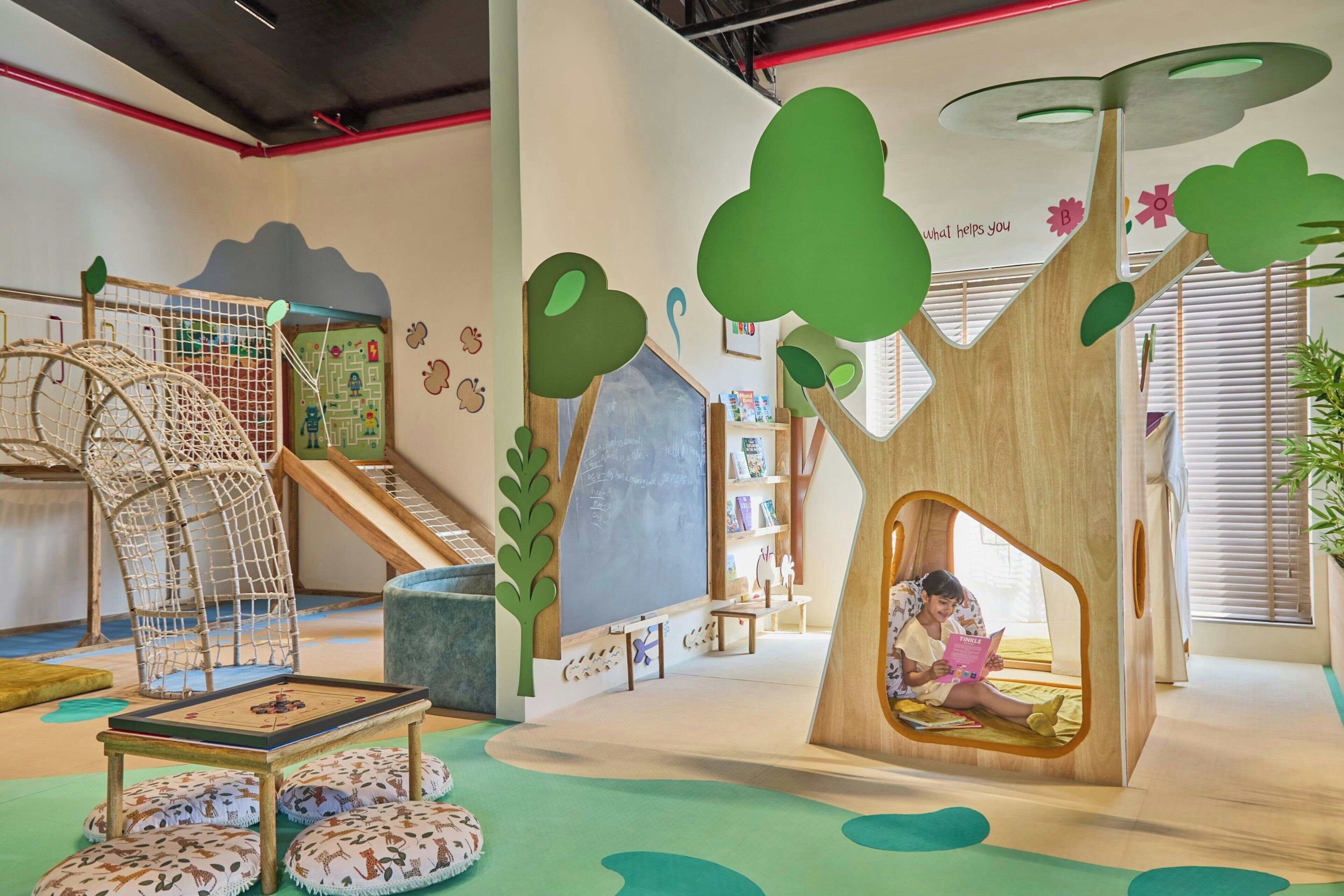 Un área de juegos infantiles con un tobogán, red de escalada y un rincón de lectura.