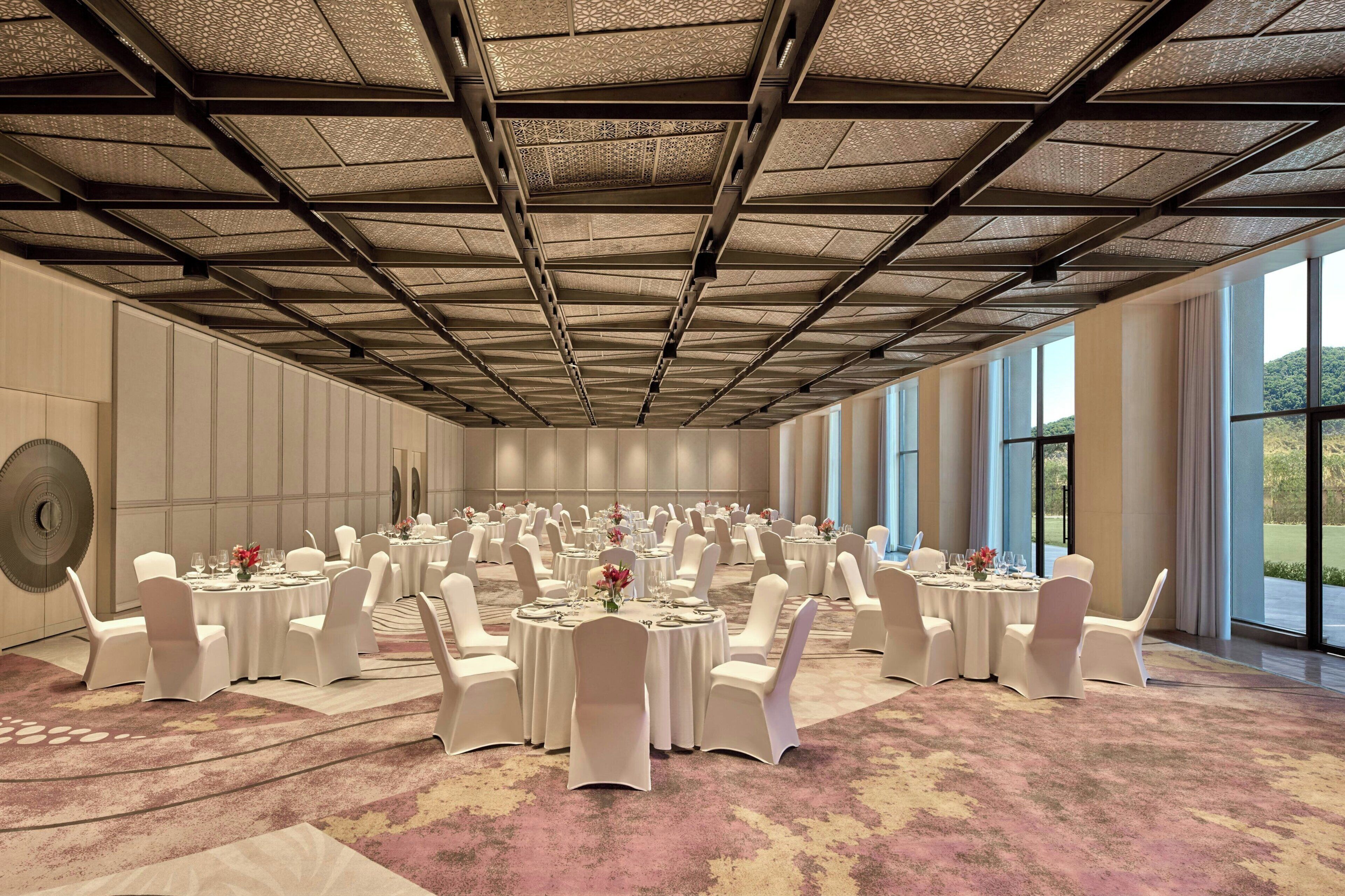 A large conference room with round tables, white chairs, and a patterned carpet.