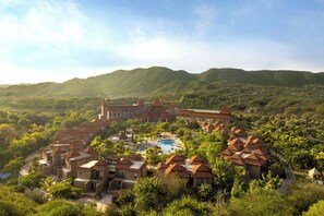 A resort with multiple buildings, a swimming pool, and a mountainous backdrop.