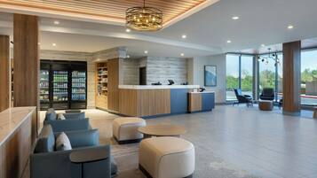 A modern lobby with seating, a reception desk, and a vending machine.