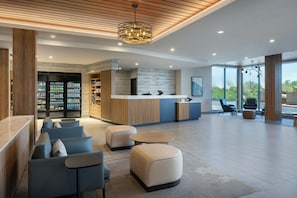 Eine moderne Lobby mit Sitzgelegenheiten, einem Empfangsbereich und einem Verkaufsautomaten.