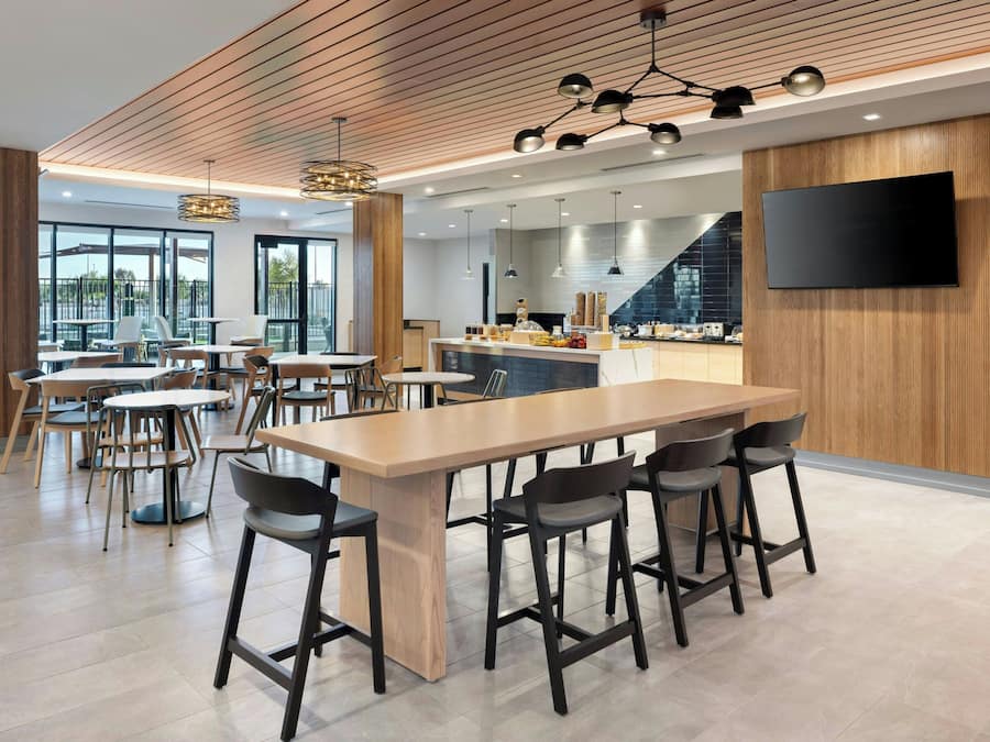 A modern restaurant with a bar area, high ceilings, and large windows.