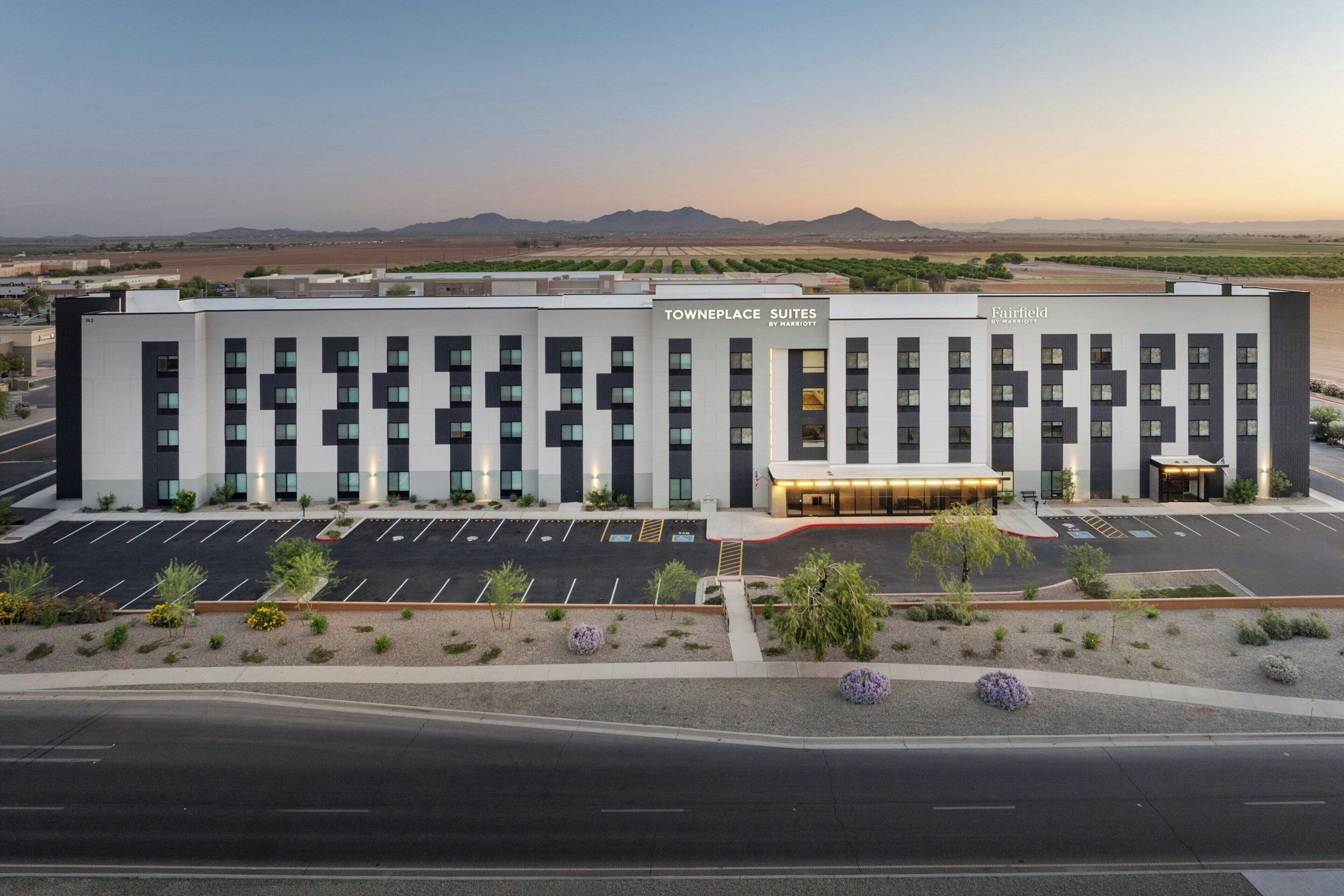 Un moderno edificio de hotel con un estacionamiento adelante, identificado como 'Fairfield by Marriott'.