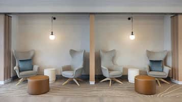Une pièce moderne avec deux fauteuils, une petite table d’appoint et une table ronde en bois.