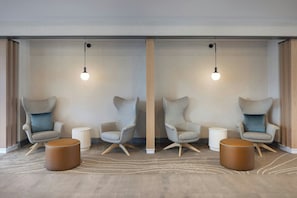 Una habitación moderna con dos sillones, una mesita auxiliar y una mesa redonda de madera.