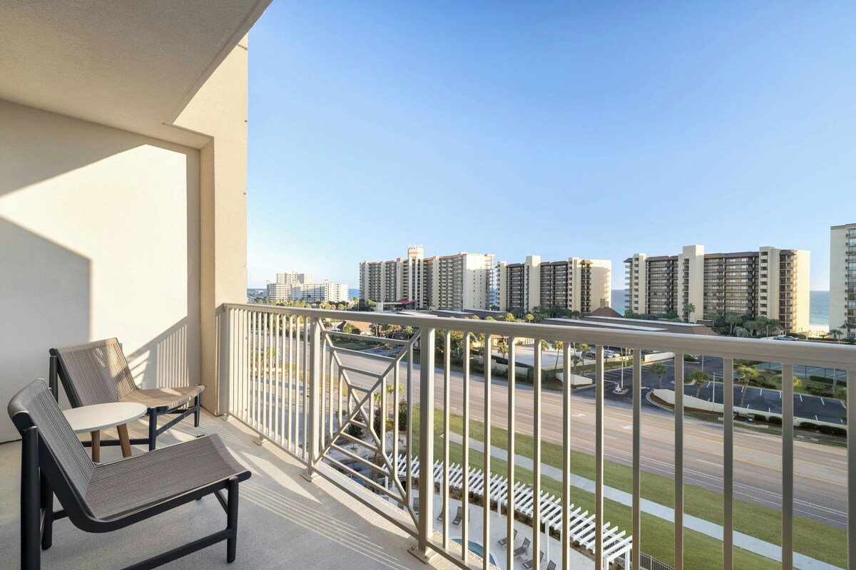 Ein Balkon mit Blick auf eine Stadtlandschaft, mit Hochhäusern und einer Straße.