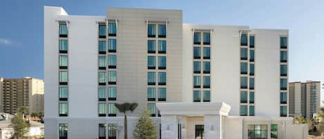 A modern hotel with a symmetrical facade, multiple floors, and a central entrance with a landscaped area in front.