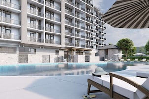 Una piscina al aire libre, sombrillas, sillones reclinables de piscina