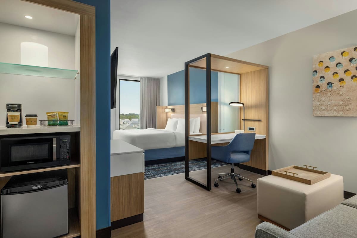 Une chambre d’hôtel équipée d’un lit, d’un bureau, d’une chaise et d’un petit coin cuisine.