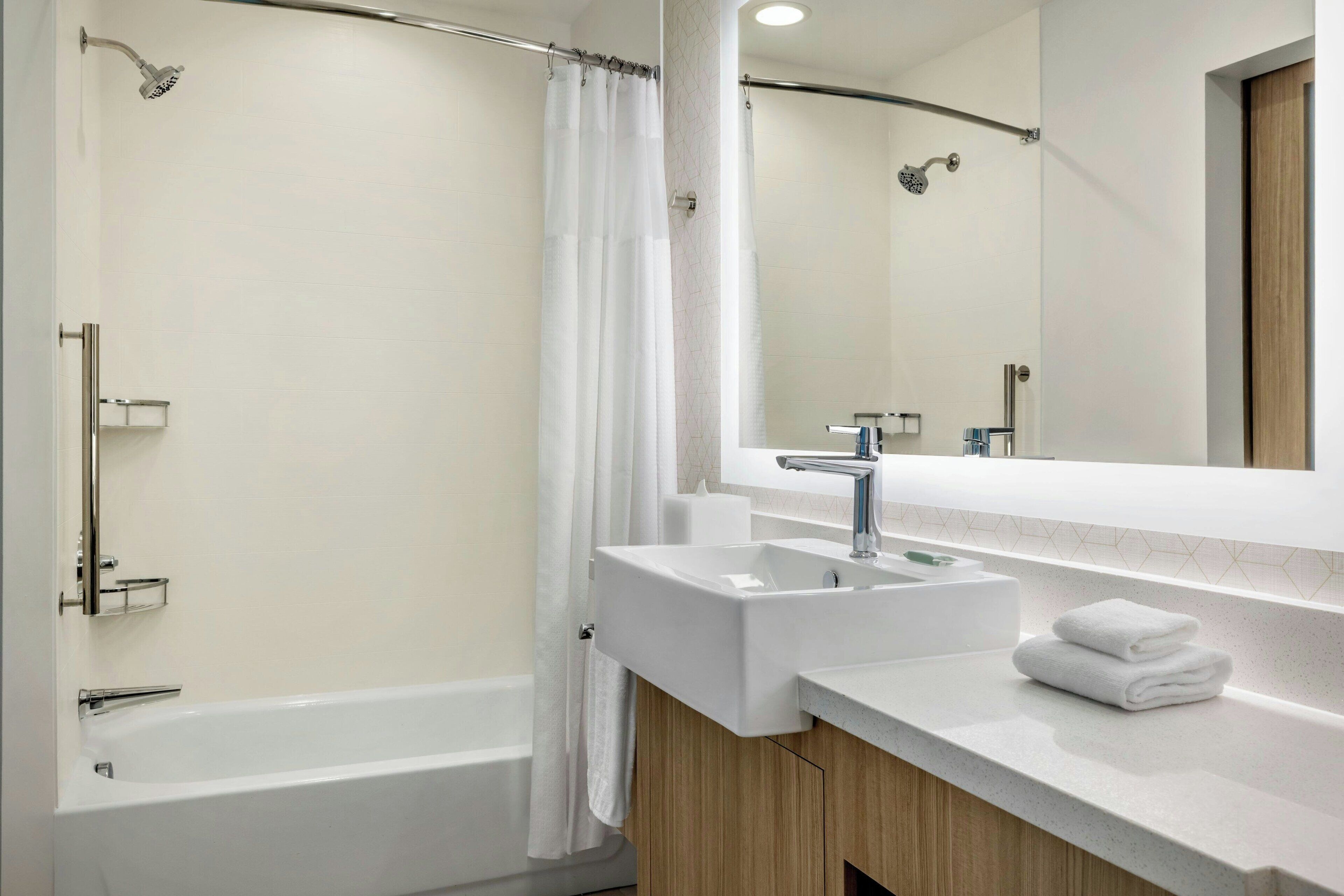 A modern bathroom with a bathtub, a shower, and a sink with a mirror above it.