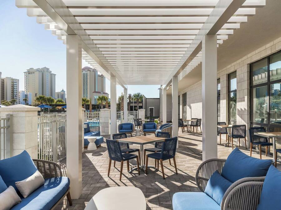 An outdoor patio with seating arrangements, a pool, and city views.