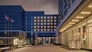 Un moderno edificio de hotel con una entrada destacada, ventanas amplias y una fachada bien iluminada.