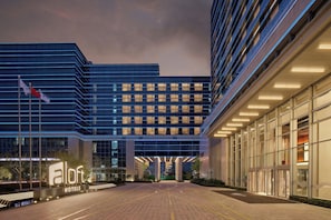A modern hotel building with a prominent entrance, large windows, and a well-lit facade.