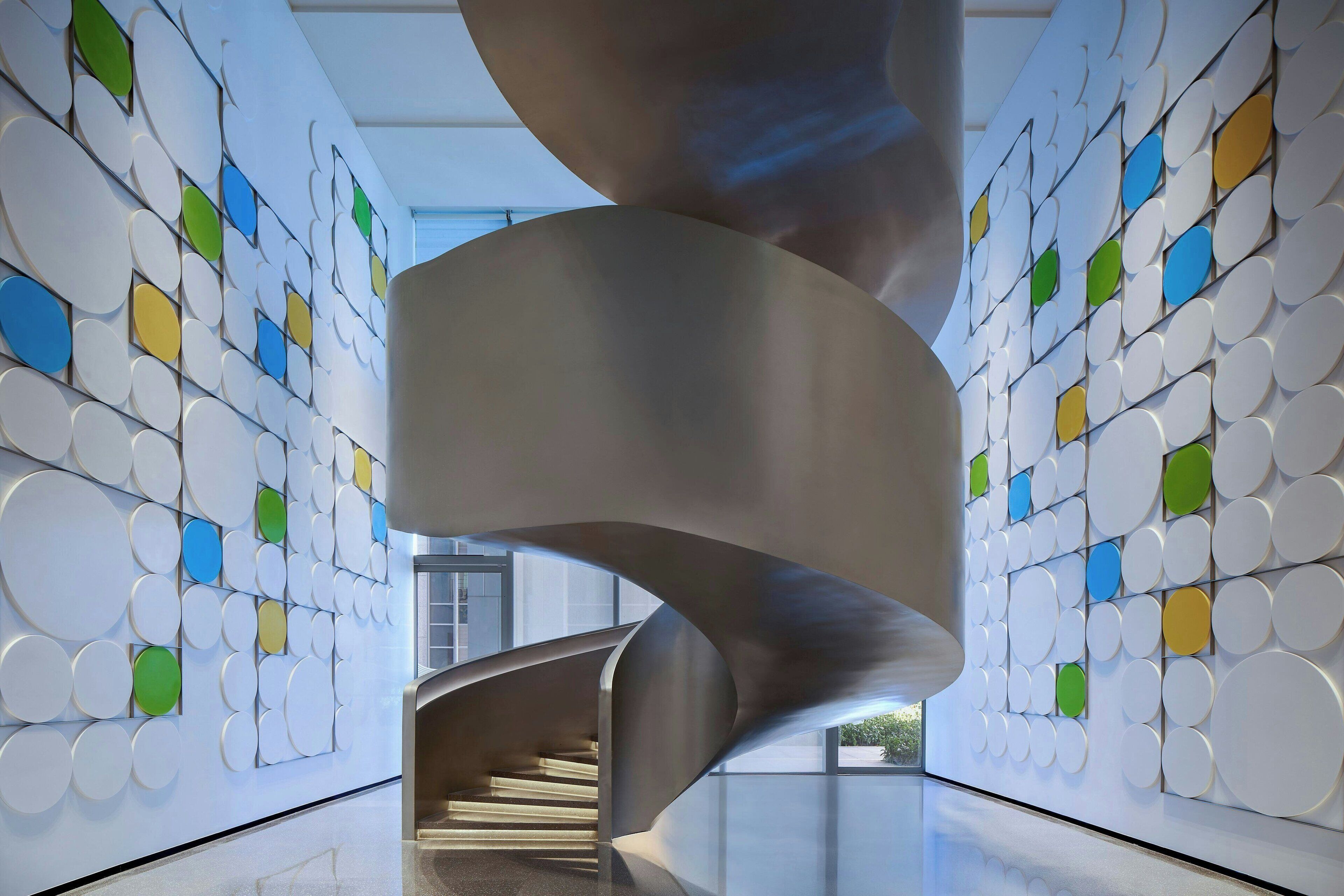 A spiral staircase in a modern interior with a patterned wall.
