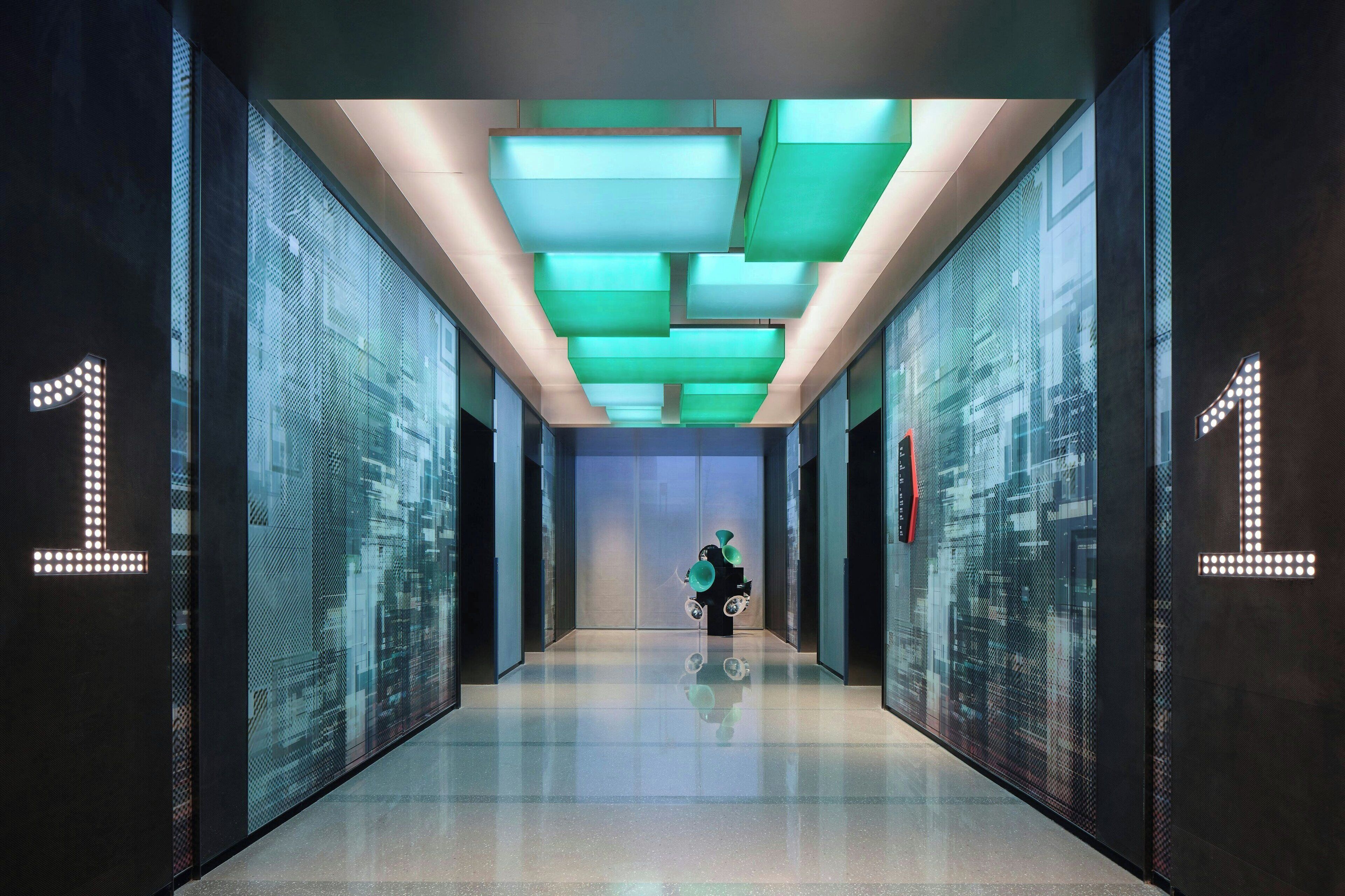 A modern hallway with reflective floors and glass walls, featuring illuminated '1' signs on the walls.