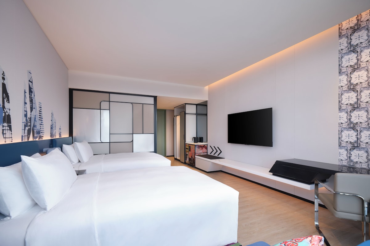 Habitación de hotel moderna con una cama grande, un escritorio, un televisor de pantalla plana y un área de descanso.