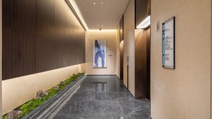 A modern hallway with a marble floor, wooden panel walls, and a reception desk with a sign. - Fairfield By Marriott Shanghai Qingpu (Shanghai)