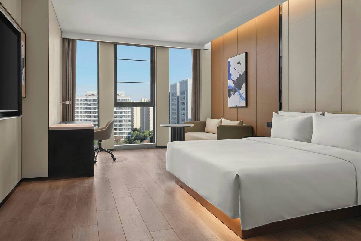 Una habitación de hotel moderna con una cama grande, un escritorio y vistas a rascacielos.
