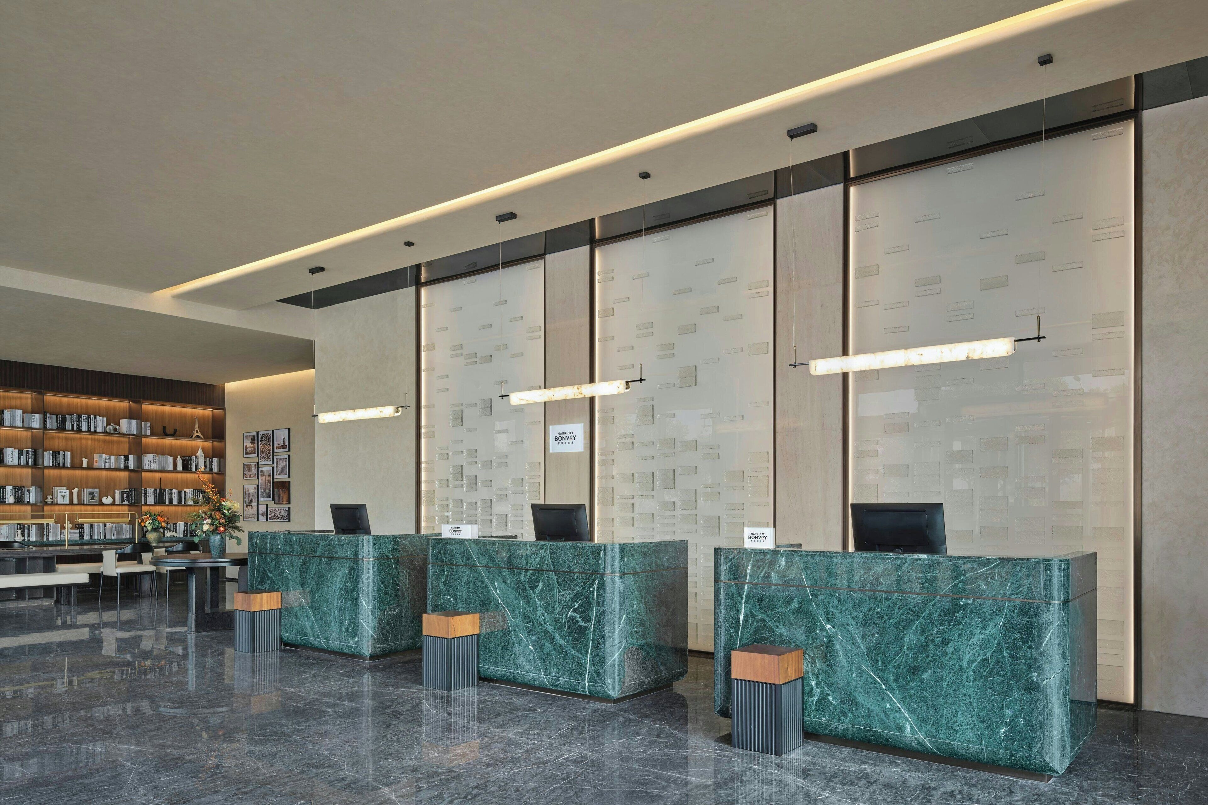 Un área de recepción moderna con mostradores de mármol, una estantería y un piso limpio y pulido.