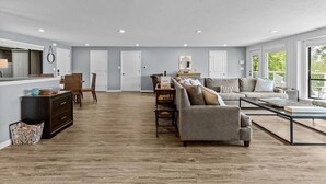 Un salon spacieux comprenant un grand canapé, une table basse et un coin repas avec des chaises et une table.