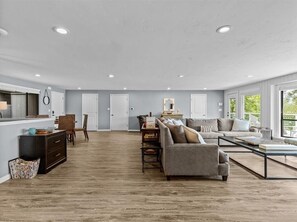 Ein großzügiges Wohnzimmer mit einer großen Couch, einem Couchtisch und einem Essbereich mit Stühlen und Tisch.