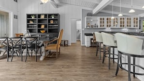 Une cuisine spacieuse avec des meubles blancs, un coin repas comprenant une table et des chaises en bois, et un bar avec des tabourets.
